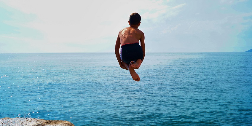 A person is shown jumping off a cliff. One of the most thrilling adventure sports in Bali