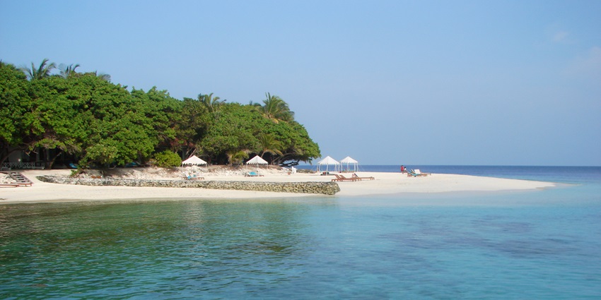 A picture of a private island in Maldives with a majestic blue sea in front of it