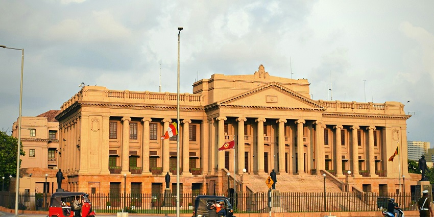A picture of the Old Parliament building in Colombo with cloudy sky in the background.