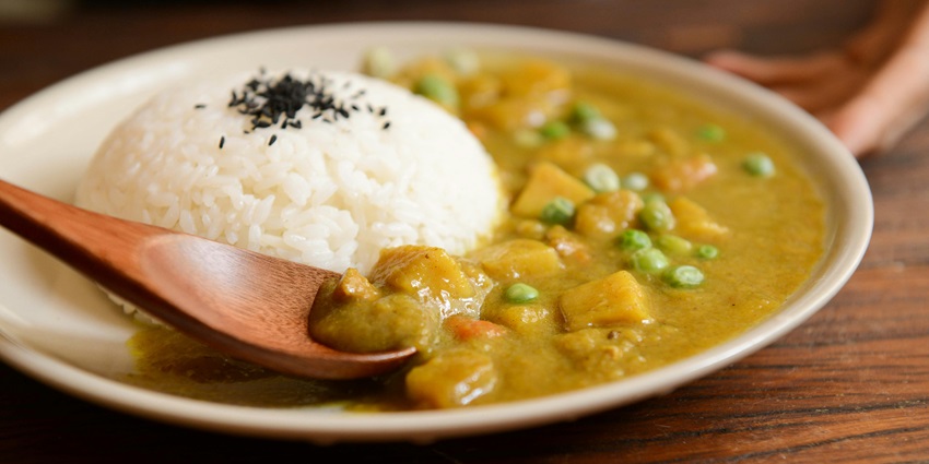 Cooked rice and curry served on a white plate, showcasing a delicious and flavorful meal.