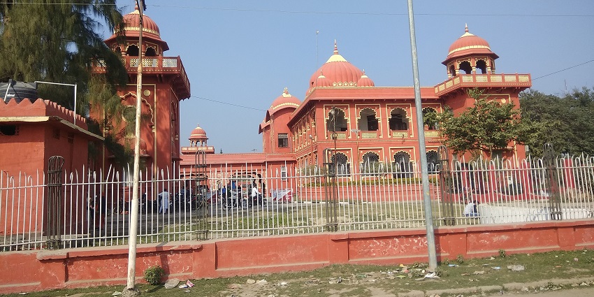 Darbhanga Raj Kila with grand, weathered walls, arched windows, and lush green surroundings.