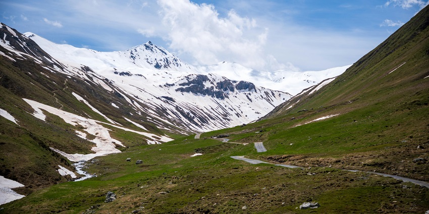 A scenic view of lush green rolling fields and snow-capped mountains of this place.