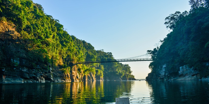 A mesmerising scenic view of the Umngot River bridge surrounded by lush greenery.