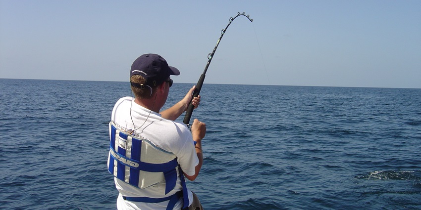 A picture of a tourist enjoying fishing at a water body in Naggar using modern equipment
