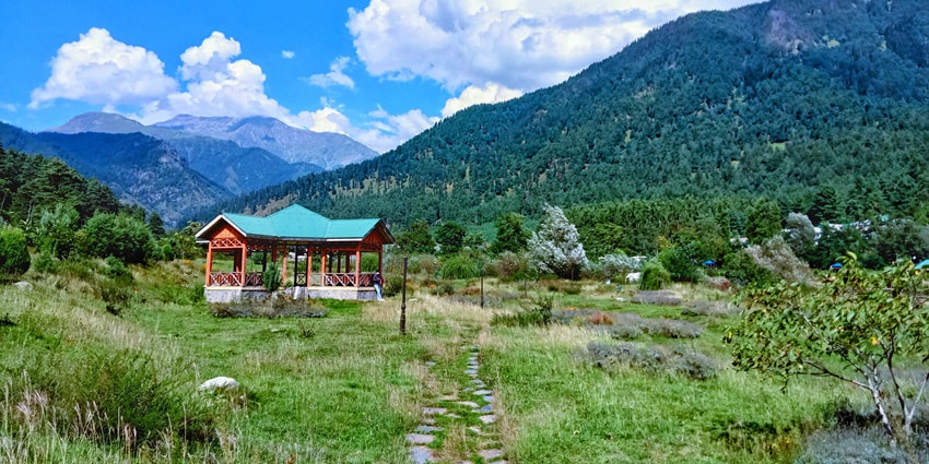 A picture of a tranquil valley with a cover of lush greenery and a small shack in sight