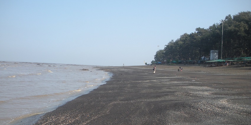 Devka Beach in Daman with waves crashing at high tide and sandy shoreline visible.