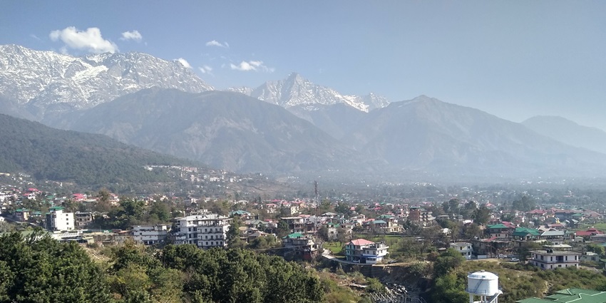 Scenic view of Dharamshala town with mountains and forests—hill stations in north india