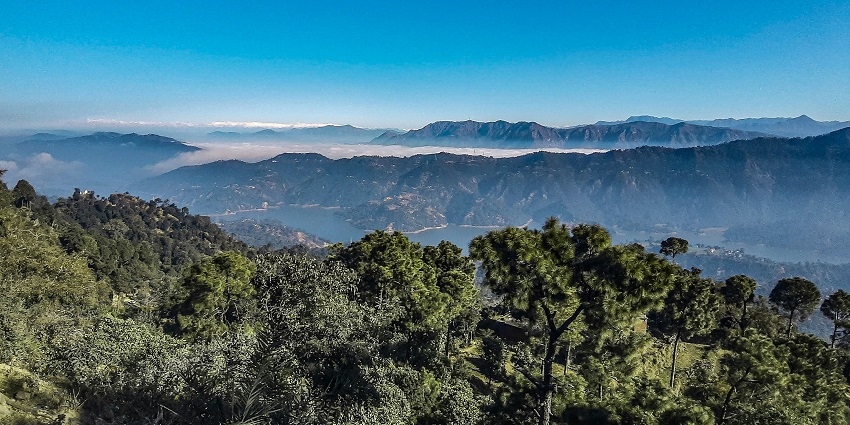Scenic view of a mountain range with lush trees and majestic peaks in the background.
