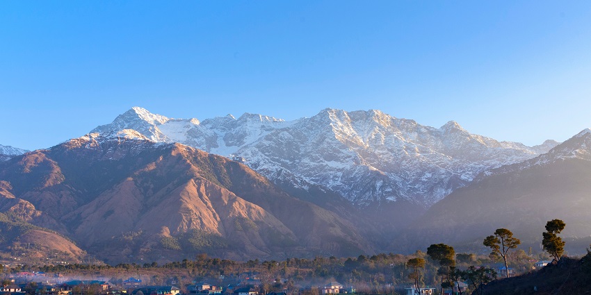 Stunning view of the Dhauladhar ranges with lush greenery and clear blue skies.