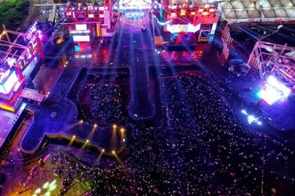 An aerial picture of a music festival happening during night time with a big crowd