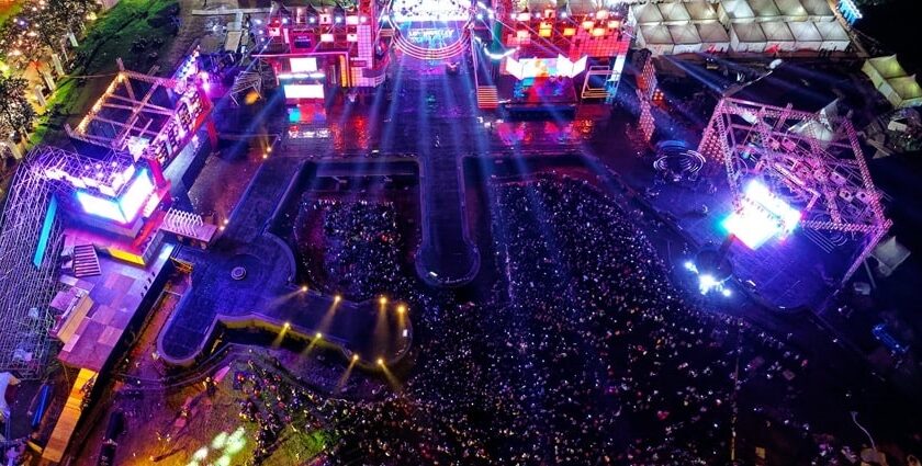 An aerial picture of a music festival happening during night time with a big crowd