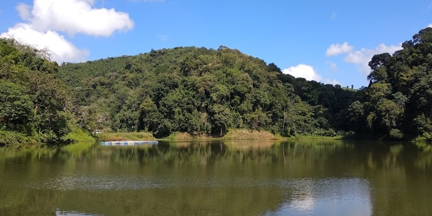 A scenic view of Tam Dil Lake near Saitual, surrounded by lush green hills.