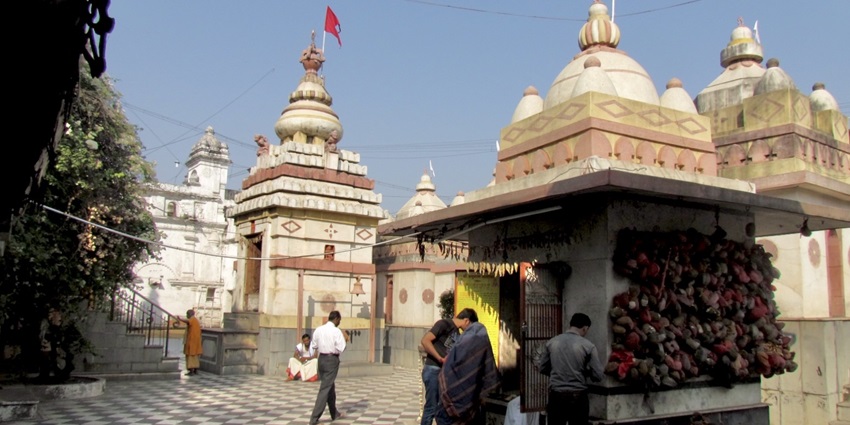 A picture of a temple complex in Jammu with decorated gopurams and red flags
