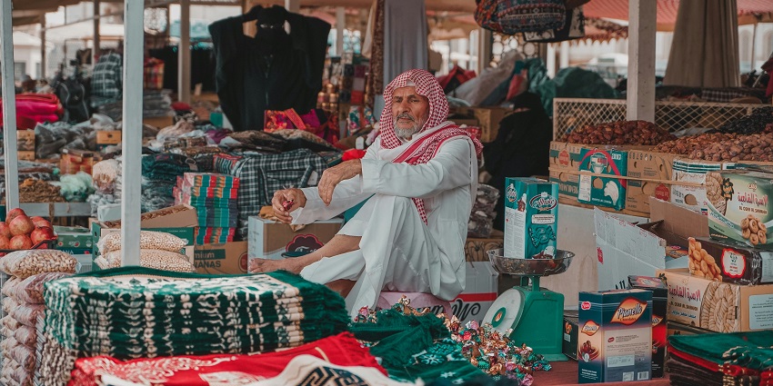 A picture of a stall at an open market in Dubai, selling fabrics and dry fruits