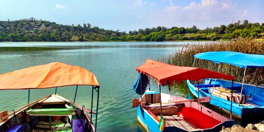 Image of a lake with clear blue water and boats near the dock for tourists to enjoy ride