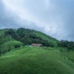 A picture with lush greenery and clouds surrounding it, making it a scenic view to witness.