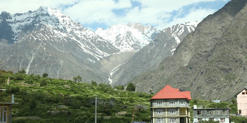 Clear image of the snow laden mountain surrounded by the beautiful forest and hills