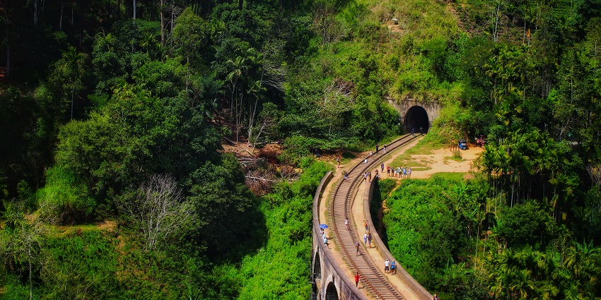 A serene view of Ella, Sri Lanka, showcasing lush green hills and a vibrant blue sky.