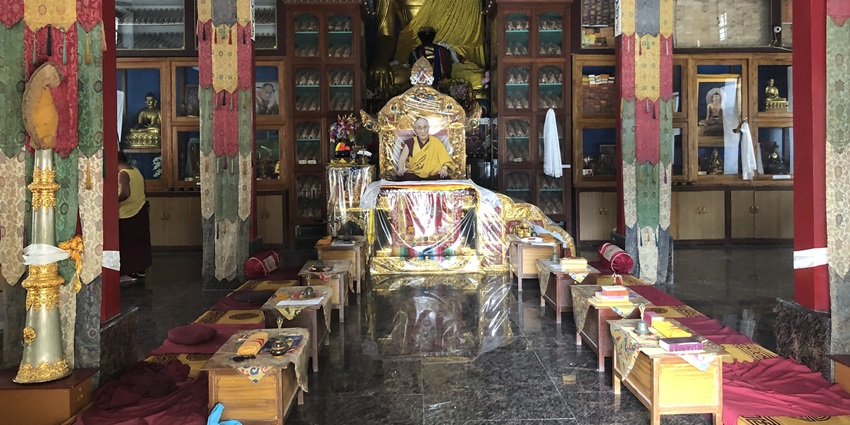 A picture of the interiors of a monastery with a monk sitting around the prayer sanctum