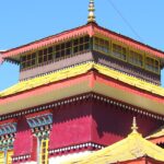 A stunning view of a monastery in Sikkim with red and yellow architecture during the day.