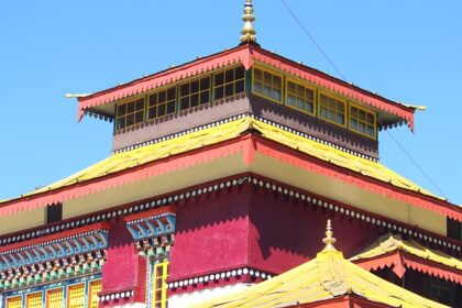 A stunning view of a monastery in Sikkim with red and yellow architecture during the day.