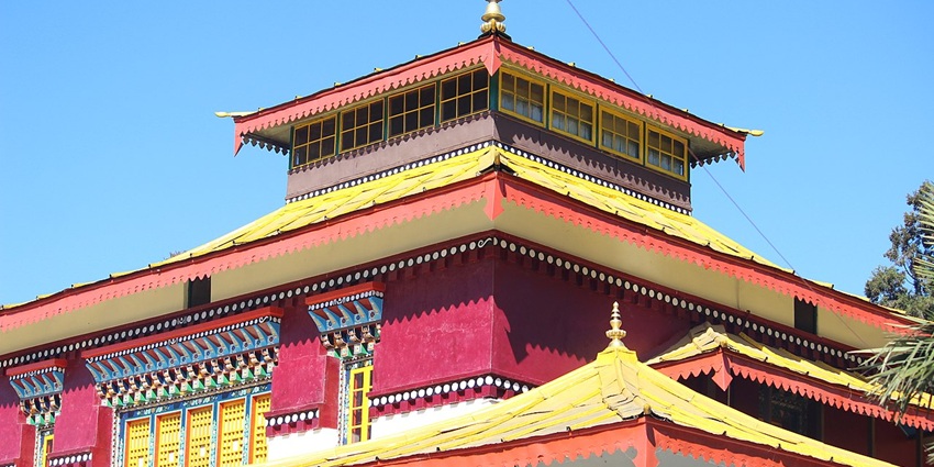 A scenic view of the majestic Enchey Monastery with a serene backdrop of lush hills and clear skies