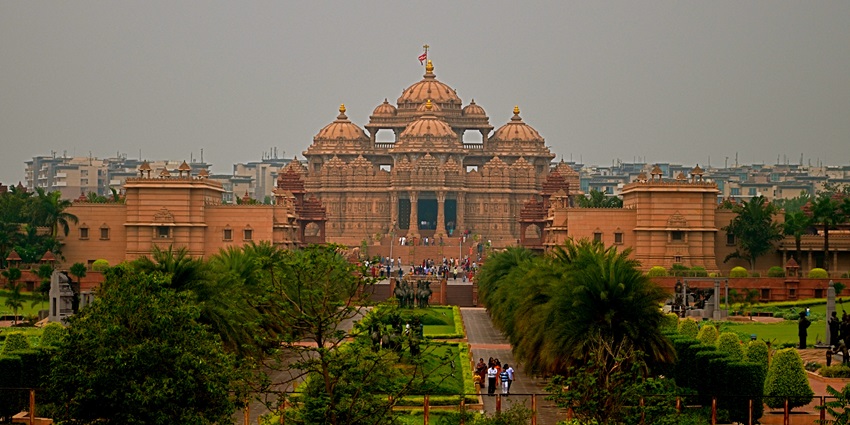 A frontal view of a majestic temple in Delhi with a lush garden in front of it