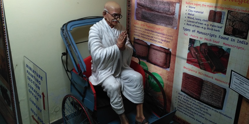 A picture of a wax statue of Mahatma Gandhi sitting on a rickshaw at a museum in Shimla
