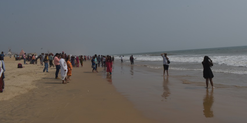 Chandrabhaga Beach in Odisha with golden sand, gentle waves, and a clear blue sky.