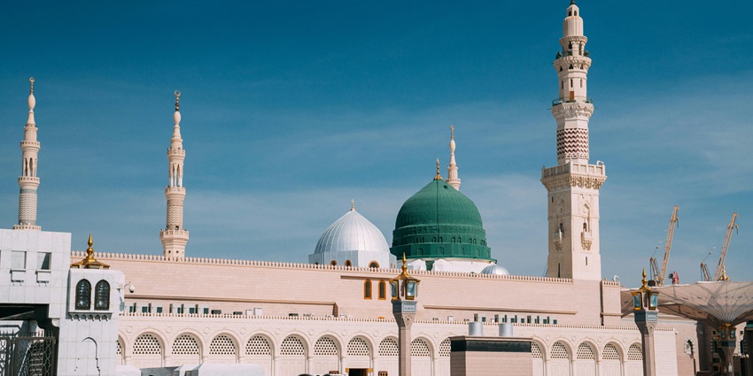 Mosque in Medina with green dome and minarets under clear sky.