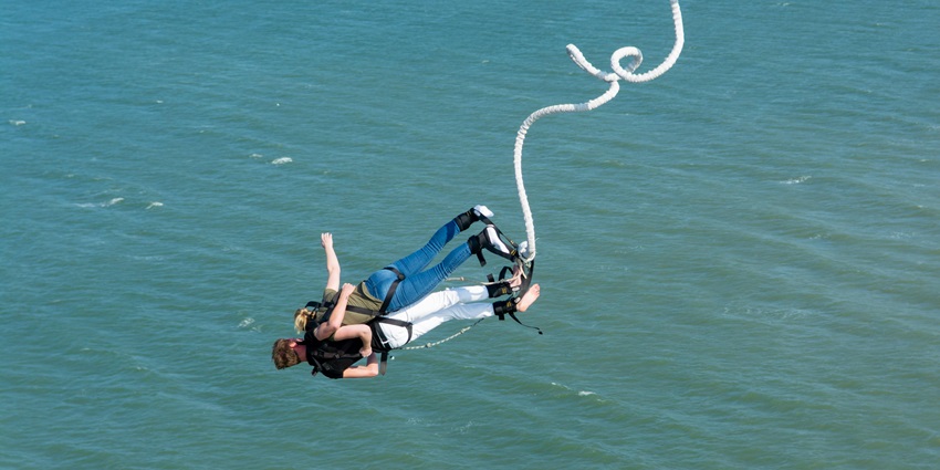 An image of bungee jumping in Thailand and jumper enjoying the freefall over a lagoon.