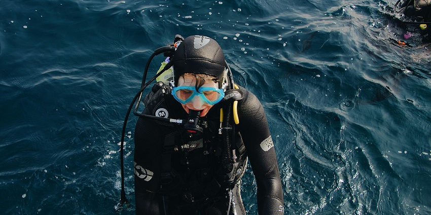 A scuba diver climbing back on his boat after taking a dive into the deep ocean