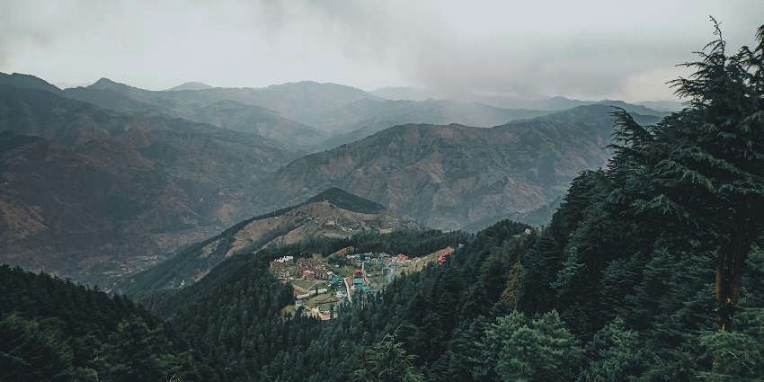 A stunning aerial view of Fagu in Himachal Pradesh with lush green meadows and houses.
