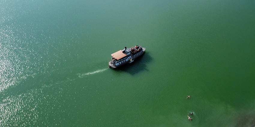 Carrying passengers across calm waters with scenic coastal views in the background.