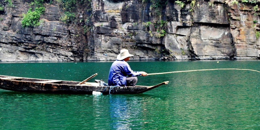Picture of a tourist fishing in the crystal-clear waters of the famous Umngot River.