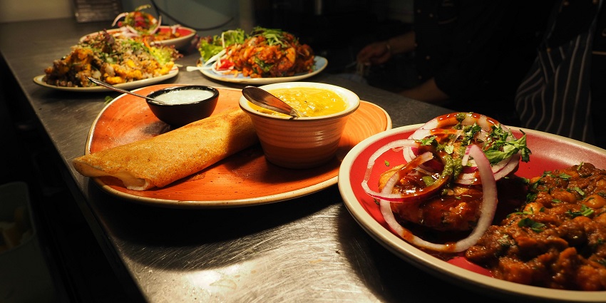 A colourful platter filled with various delicious foods, including fruits, cheeses, and meats.