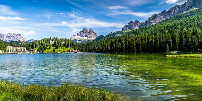 Green trees near the lake under blue sky and the scenic enchanting views of the hill
