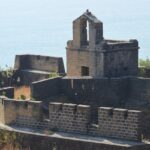 A breathtaking view of the Diu Fort with a water body on the side covered in greenery.