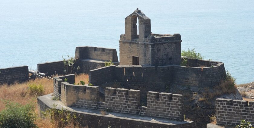 A breathtaking view of the Diu Fort with a water body on the side covered in greenery.