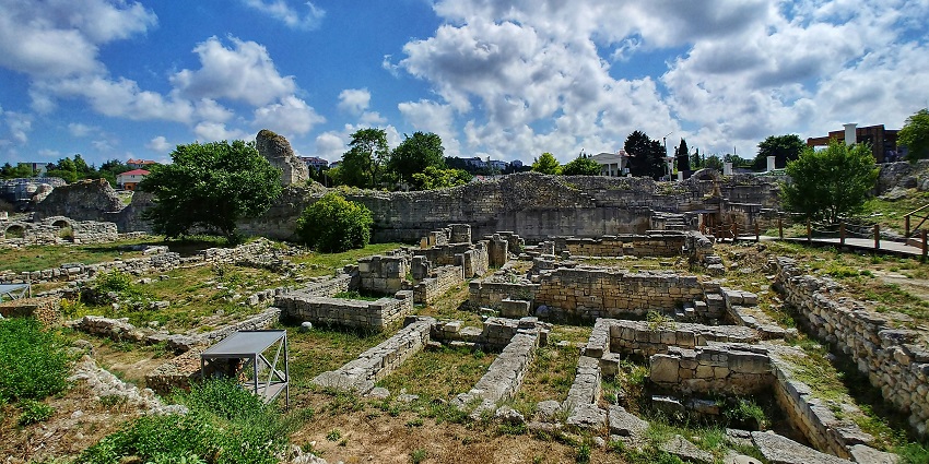 Fort ruins with ancient brick structures and grassy surroundings under a clear sky.