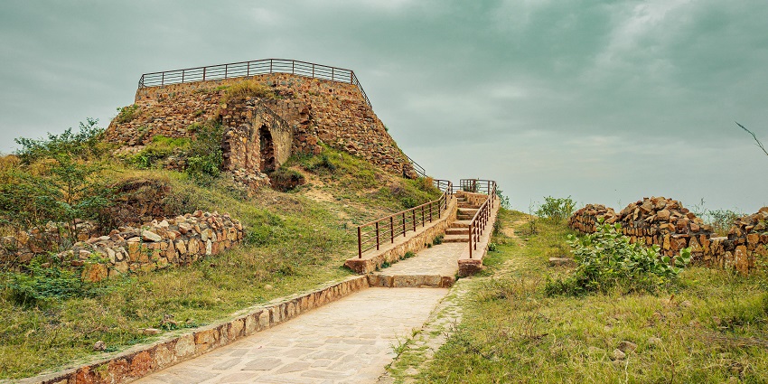 Image of ancient stone fort ruins surrounded by lush greenery under a clear blue sky.