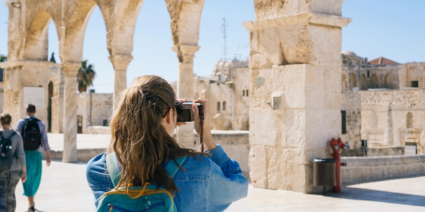 Image of a woman taking pictures of fort ruins along with the other travellers.