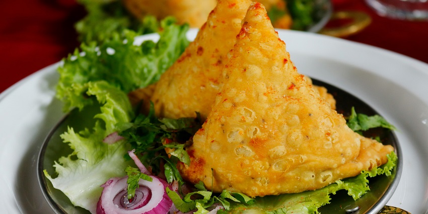 Image of crispy fried samosa arranged on a saucer, showcasing a golden-brown texture.