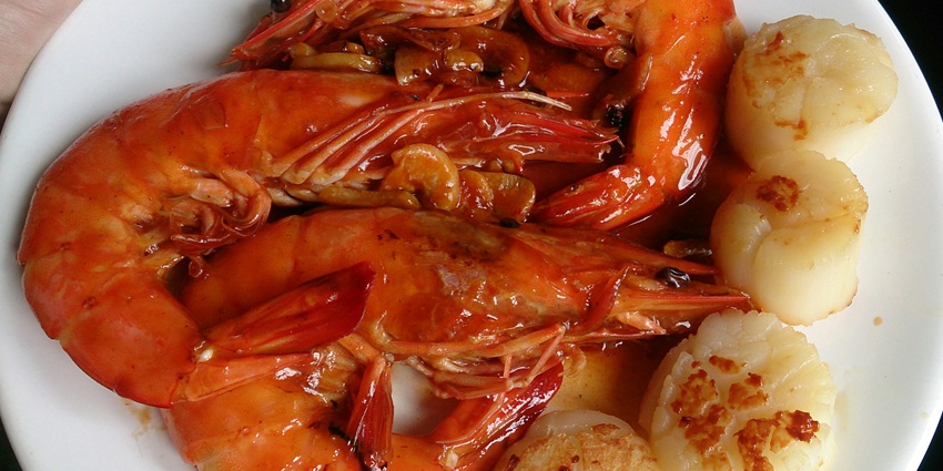 A closer look at fried prawns served on a white ceramic plate with a white dish.