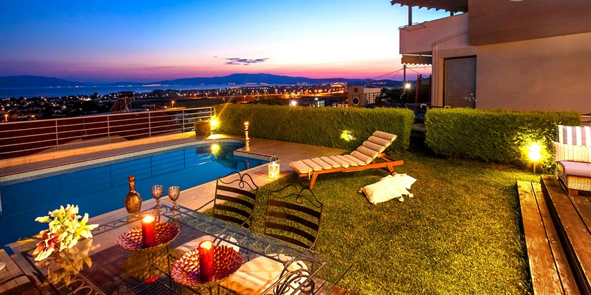 Modern house with a stylish swimming pool overlooking a scenic view at dusk.