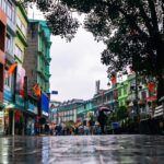 A breathtaking view of a market in Gangtok with wet roads and people walking down it.