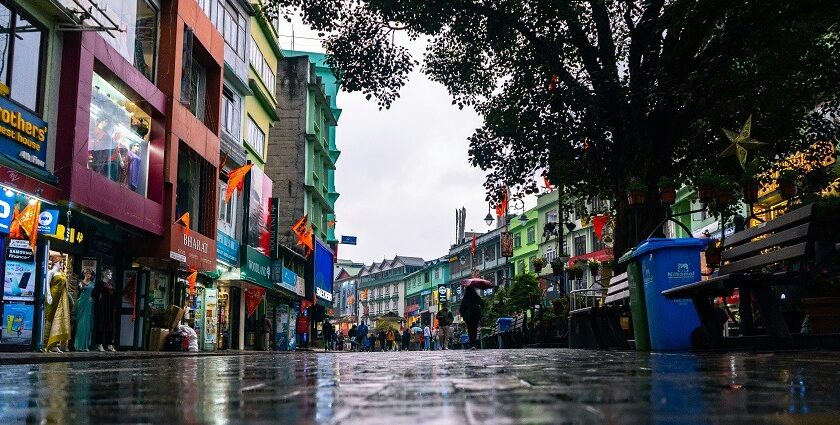 A breathtaking view of a market in Gangtok with wet roads and people walking down it.