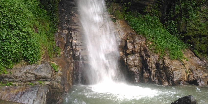 A view of a stunning waterfall in Gangtok surrounded by lush greenery during the daytime.