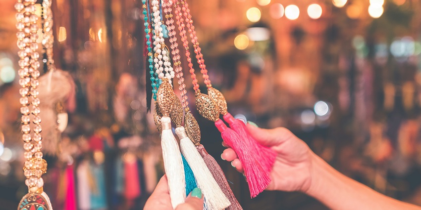 A stunning view of two hands holding assorted colourful jewellery during the daytime.