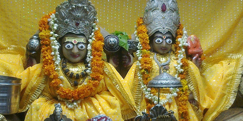 A picture of a prayer house from inside with idols of two gods in front, dressed with garlands